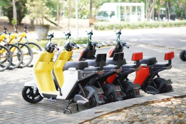 Renkli elektrikli motosikletler ziyaretçilere kiralanmak üzere turistik bir yere dizildiler.