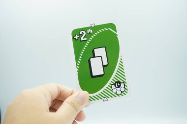 Hand holding green plus 2 cards at once all draw 1 from UNO Flex game cards (board game) with white background clipart