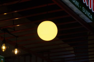 A yellow light bulb is on at a food booth in a food court clipart