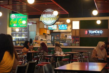 Alışveriş merkezinin içindeki atmosfer yiyecek bekleyen ziyaretçilerle dolu.