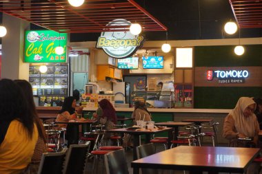 The atmosphere inside the food court in the mall with visitors waiting for food clipart