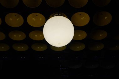 A round white lamp is burning on a dark background and a bowl clipart