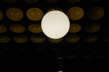 A round white lamp is burning on a dark background and a bowl clipart