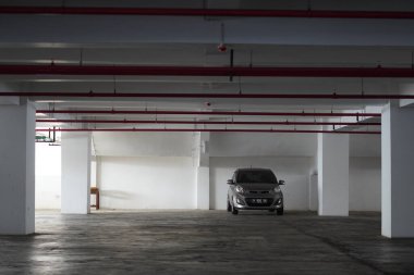 Arabaların park edildiği bir binanın bodrumu boş ve sadece bir sedan ile dolu.