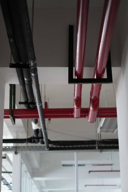 Çok katlı bir binanın tavanında farklı renkte borular var.