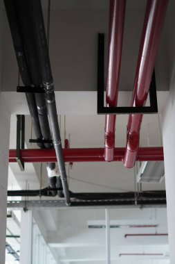 Çok katlı bir binanın tavanında farklı renkte borular var.