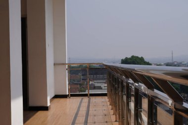 Gümüş parmaklıklı yüksek bir binanın balkonunda güneş ışığı görülür.