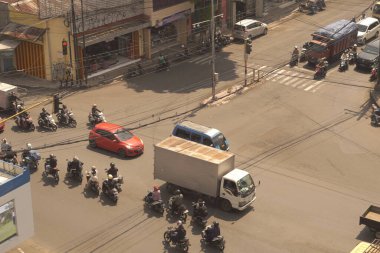 Cars and motorbikes crossing major road junctions with old buildings in Indonesia with retro vibes clipart