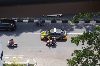 Busy roads in Indonesia that are actively traversed by vehicles and are photographed from above clipart