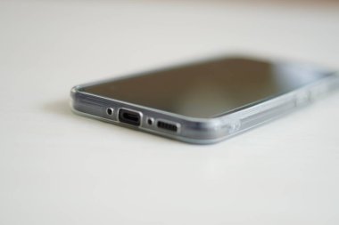 C tipi bir USB portu, hoparlör deliği ve mikrofon deliği olan bir akıllı telefonun alt kısmı beyaz bir masaya yerleştirilir.