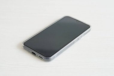 Net bir davası olan akıllı bir telefon beyaz bir masada yatıyor.