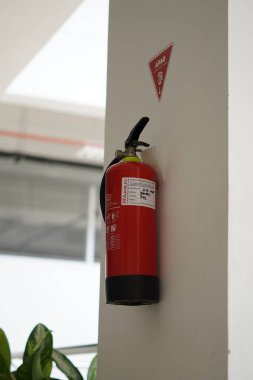 Minimalist bir binanın duvarına bağlı bir yangın söndürücü.