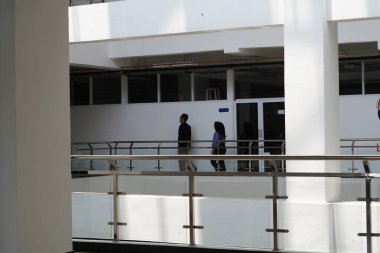 Bir kadın ve bir erkek gün boyunca minimalist, çok amaçlı bir binada yürüyorlar.