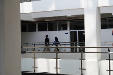 Bir kadın ve bir erkek gün boyunca minimalist, çok amaçlı bir binada yürüyorlar.