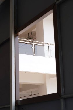 Minimalist, beyaz, çok katlı bir binanın balkonunda alt pencereden görüldü.