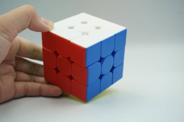 Sol el, beyaz bir arka planda 3x3 rubik karıştırılmamış tutar.