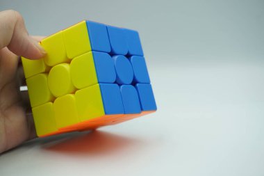 Sol el, beyaz bir arka planda 3x3 rubik karıştırılmamış tutar.