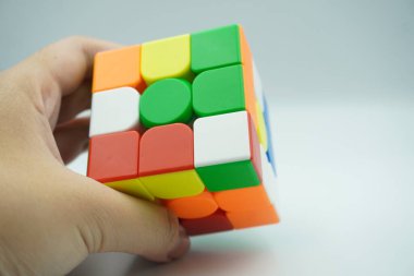 Sol elde 3x3 rubik var. Beyaz arka planda şifrelenmiş.