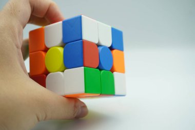 Sol elde 3x3 rubik var. Beyaz arka planda şifrelenmiş.