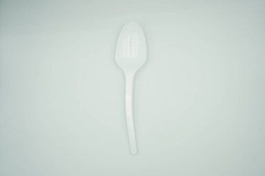 Beyaz arka planda kıvrımlı bir plastik kaşık.
