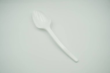 A curved white plastic spoon on a white background clipart