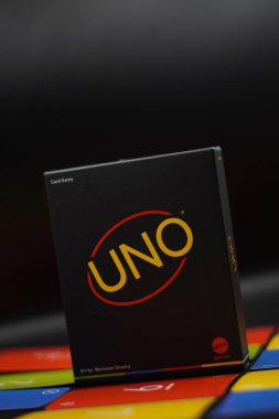 A minimalist black Uno card game box standing among cards with a black background clipart