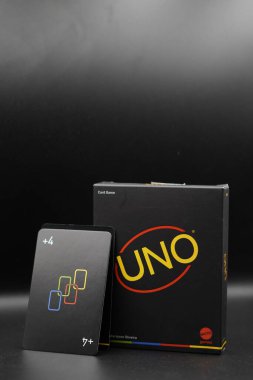 +4 card resting on a black Uno card game box with a black background clipart