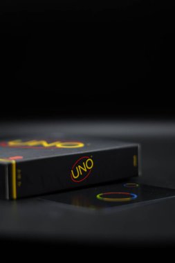 Uno writing on Uno card game box placed on black background clipart