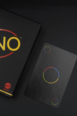 Uno Minimalista black playing card box with color changing cards on the side with black background clipart