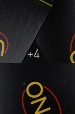 The number +4 among a pile of black Uno Minimalista playing cards in the shape of a triangle on a black background clipart