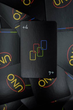 The +4 card is between the black Uno Minimalista cards with a black background. clipart