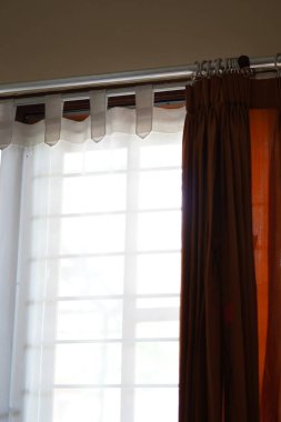 Çardaklı bir evin penceresinde gün boyunca açık olan perdeler