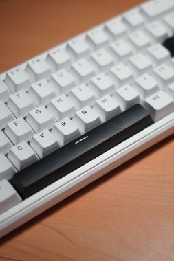 Tahta bir masa üzerinde monokrom (siyah ve beyaz) temalı% 65 mekanik klavye.