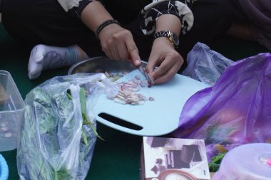 Bir kadının eli gün boyunca kırmızı soğan kesiyor.