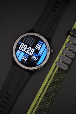 Yanındaki siyah arkaplanlı kumaş kayışıyla aydınlatılmış spor tasarımı olan siyah akıllı saat.