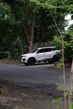 Büyük ağaçlı sessiz bir yolun kenarına beyaz bir minibüs park edilmişti.