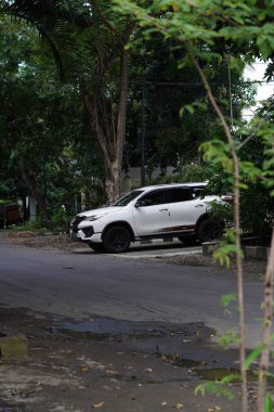 Büyük ağaçlı sessiz bir yolun kenarına beyaz bir minibüs park edilmişti.