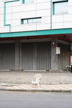 Dükkânın önündeki kaldırımda plastik sandalyeler.