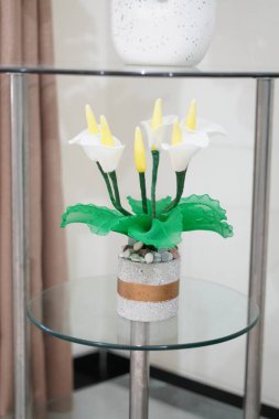 Oda dekorasyonu için eşsiz yuvarlak bir tencerede yapay beyaz zambaklar.