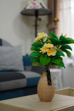 Oda dekorasyonu için eşsiz yuvarlak bir tencerede suni beyaz frangipani çiçekleri.