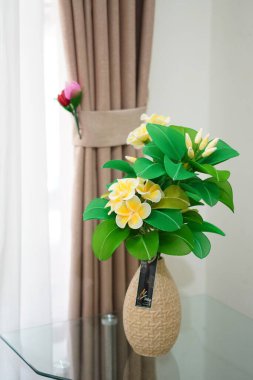 Oda dekorasyonu için eşsiz yuvarlak bir tencerede suni beyaz frangipani çiçekleri.