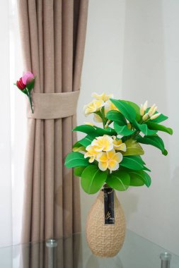 Oda dekorasyonu için eşsiz yuvarlak bir tencerede suni beyaz frangipani çiçekleri.