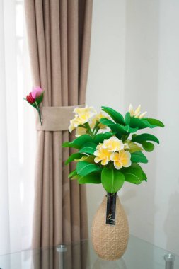 Oda dekorasyonu için eşsiz yuvarlak bir tencerede suni beyaz frangipani çiçekleri.