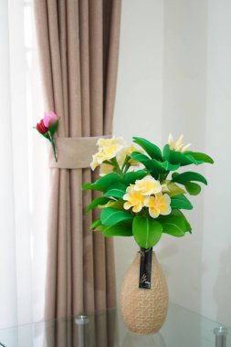 Oda dekorasyonu için eşsiz yuvarlak bir tencerede suni beyaz frangipani çiçekleri.