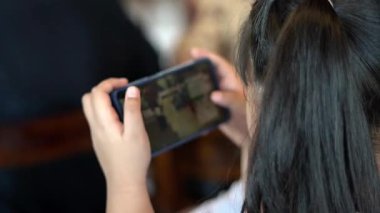 Bir kız akıllı telefonuyla bir şeyler yazarken oyun oynamakla meşgul.