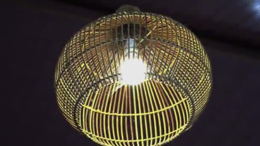 Sarı lamba süslemesi, dokuma malzemeden yapılmış yuvarlak ahşap bardaklar klasik bir izlenim veriyor.