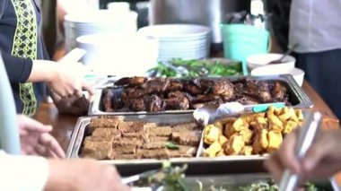 Bir kişinin eli, bir etkinlikte açık büfede öğle yemeği için meze alıyor.