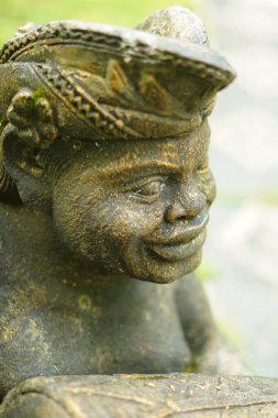 Kapalı modda tipik bir Balili baş örtüsü (udeng) takan oyulmuş taş heykelin yüzü