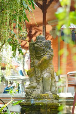 Asılı bitkileri olan bir inşaat alanında tipik bir Bali adası heykeli.