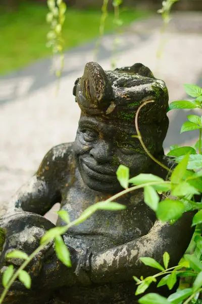 Elinde davul tutan ve çalıların arasında duran Balili bir adamın taş heykeli.